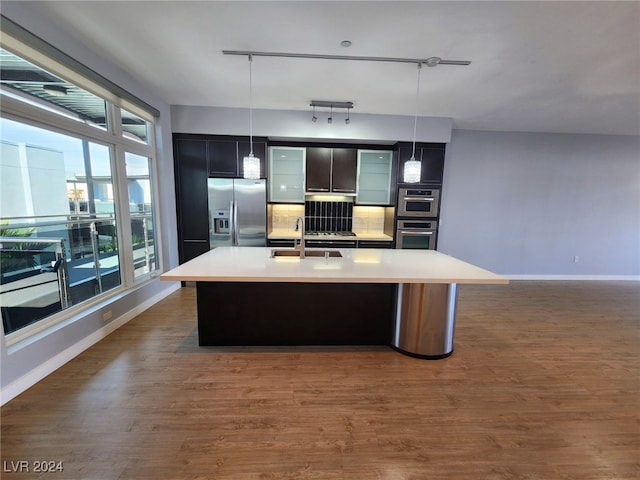 kitchen with track lighting, sink, an island with sink, appliances with stainless steel finishes, and decorative light fixtures