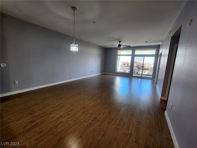 unfurnished room featuring ceiling fan with notable chandelier and dark hardwood / wood-style floors