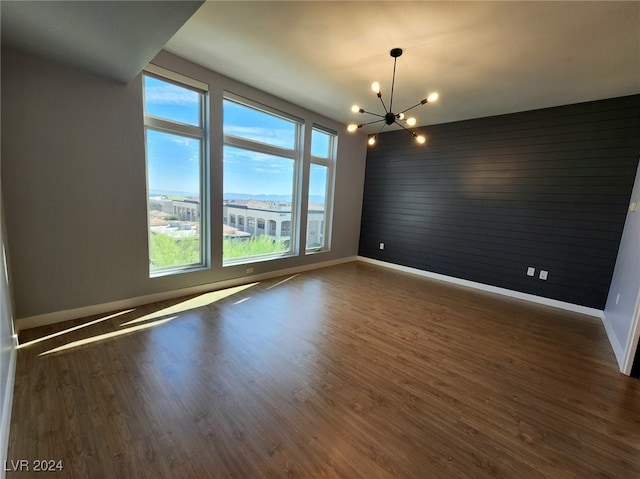 unfurnished room with a healthy amount of sunlight, dark wood-type flooring, and a notable chandelier