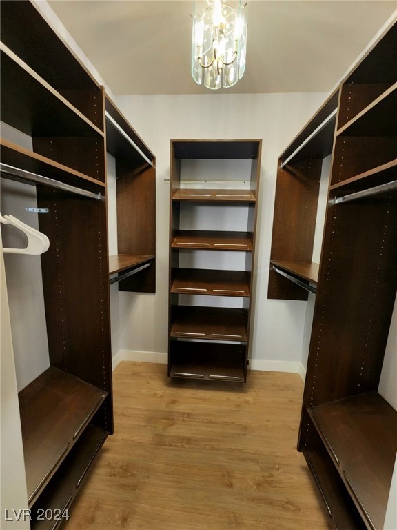 walk in closet with a notable chandelier and light hardwood / wood-style floors