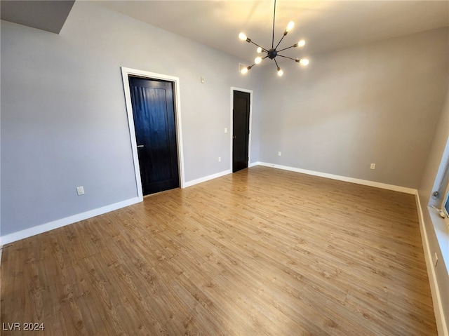 unfurnished room featuring light wood-type flooring and a chandelier