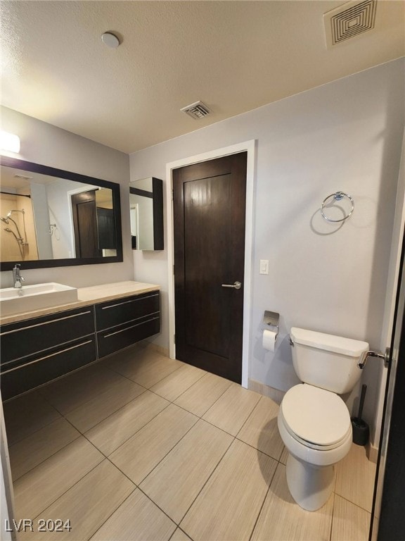 bathroom with a textured ceiling, vanity, and toilet