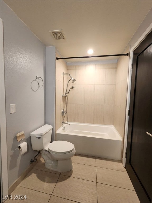 bathroom featuring tile patterned flooring, tiled shower / bath combo, and toilet