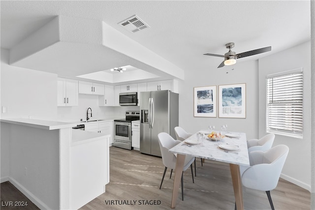 kitchen featuring appliances with stainless steel finishes, light hardwood / wood-style floors, white cabinets, a textured ceiling, and ceiling fan