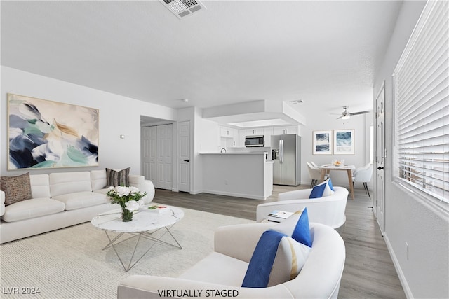 living room featuring light hardwood / wood-style floors and ceiling fan