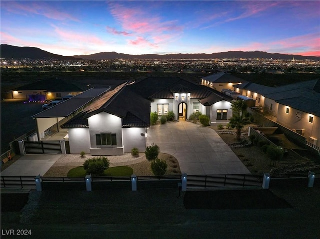 view of front of home with a fenced front yard, a mountain view, concrete driveway, a gate, and stucco siding