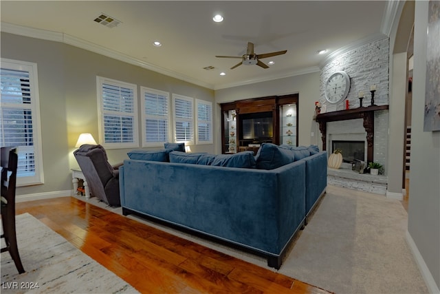 living room with ornamental molding, ceiling fan, light hardwood / wood-style floors, and a fireplace