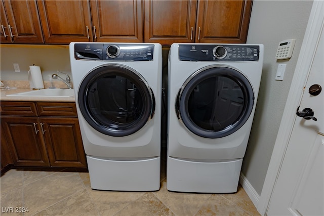 laundry area with washing machine and dryer, sink, light tile patterned floors, and cabinets