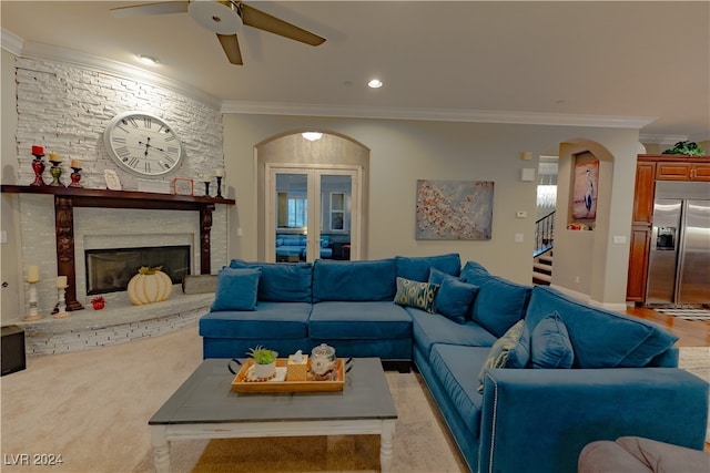 living room with a large fireplace, ceiling fan, and crown molding