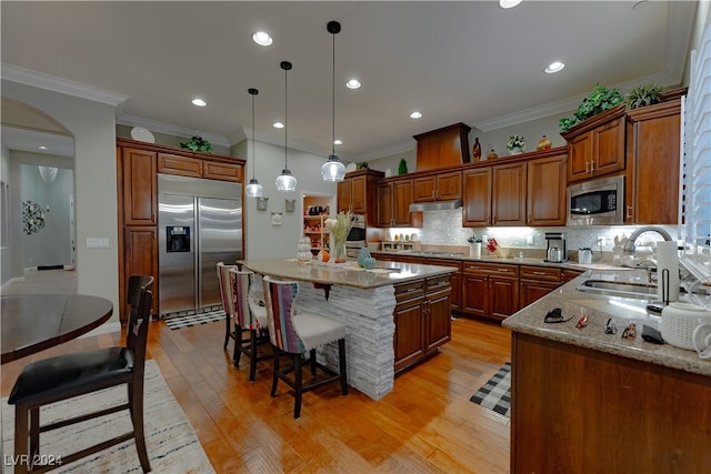 kitchen with light wood-type flooring, a center island, built in appliances, and sink