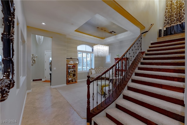 foyer with a tray ceiling and an inviting chandelier