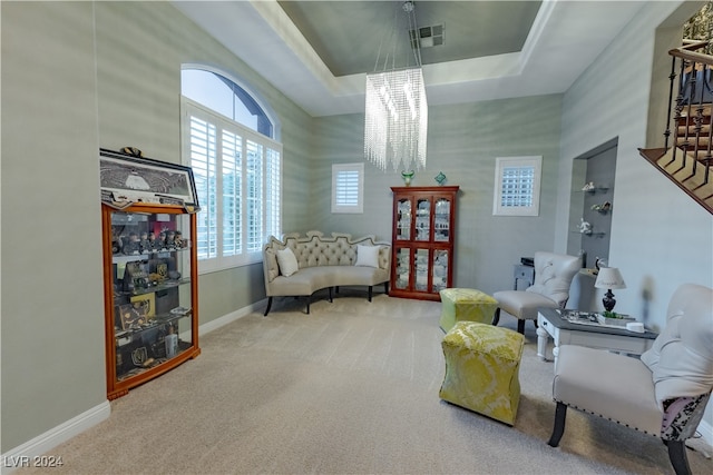 sitting room with a raised ceiling, carpet flooring, and an inviting chandelier