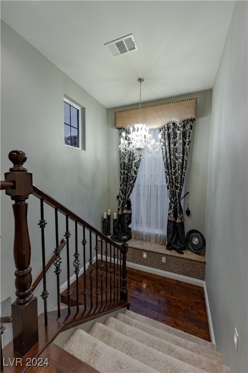 staircase with hardwood / wood-style floors and a chandelier