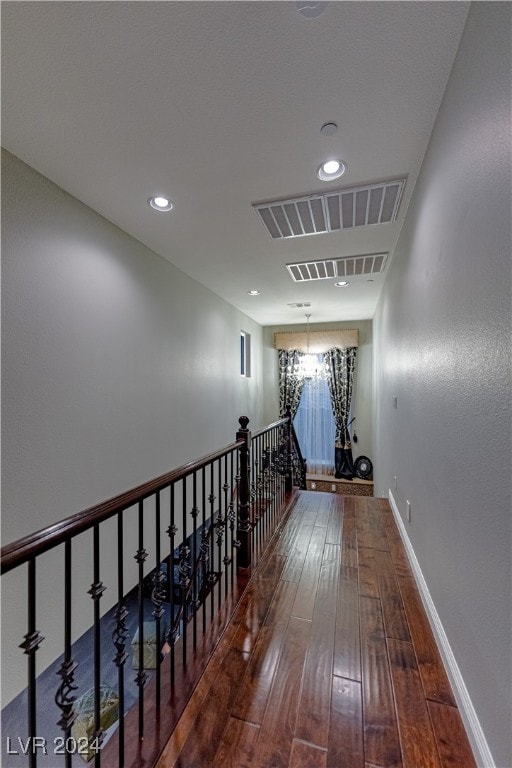 hallway featuring an inviting chandelier and hardwood / wood-style flooring