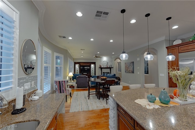 kitchen featuring light wood-type flooring, crown molding, light stone countertops, and ceiling fan