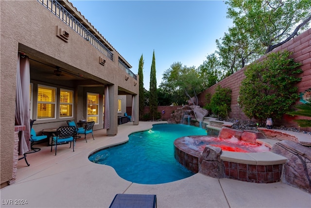 view of pool featuring ceiling fan, an in ground hot tub, a patio area, pool water feature, and an AC wall unit