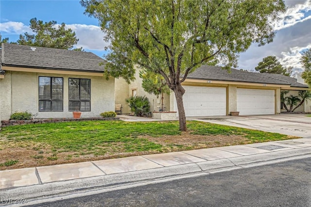 view of front of house with stucco siding, a front yard, concrete driveway, and an attached garage