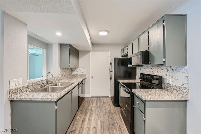 kitchen featuring tasteful backsplash, sink, light hardwood / wood-style floors, appliances with stainless steel finishes, and gray cabinets