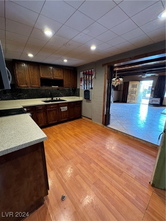 kitchen with dark brown cabinets, light hardwood / wood-style floors, tasteful backsplash, and sink