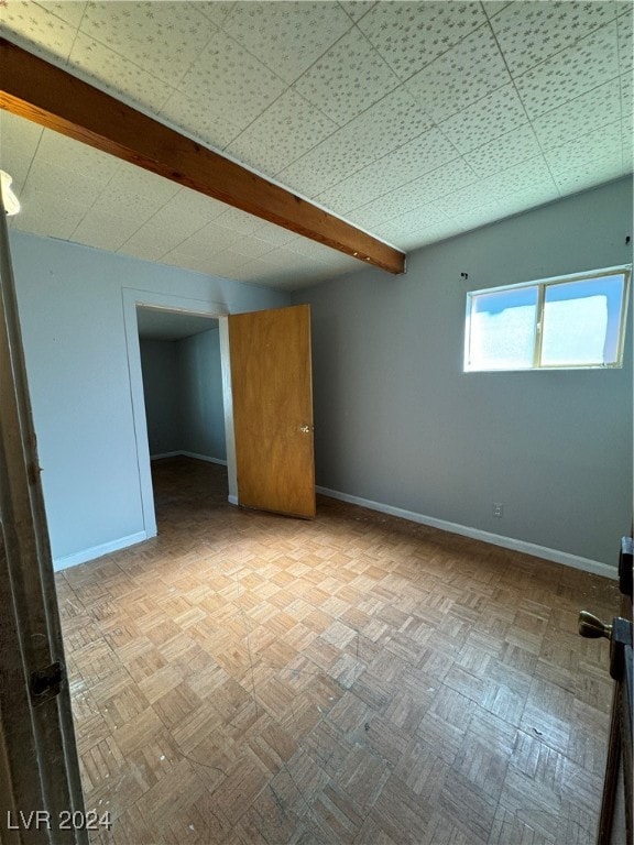 empty room with light parquet flooring and beam ceiling