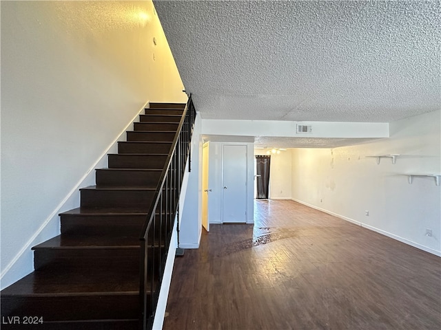 stairs with a textured ceiling and hardwood / wood-style floors