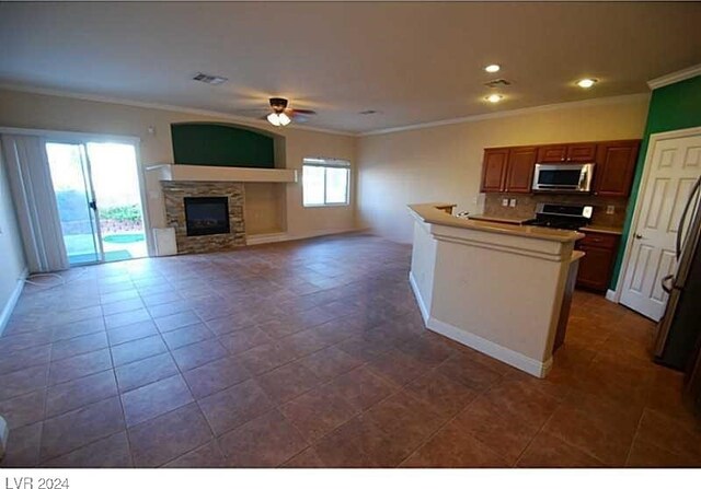 kitchen with a fireplace, stove, ceiling fan, and ornamental molding