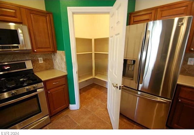 kitchen with decorative backsplash, light tile patterned floors, and appliances with stainless steel finishes