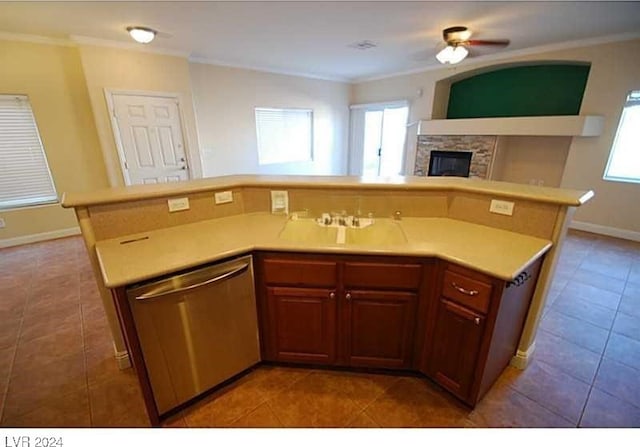 kitchen with dishwasher, tile patterned floors, crown molding, ceiling fan, and a fireplace