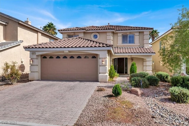 mediterranean / spanish home featuring stucco siding, an attached garage, decorative driveway, and a tiled roof