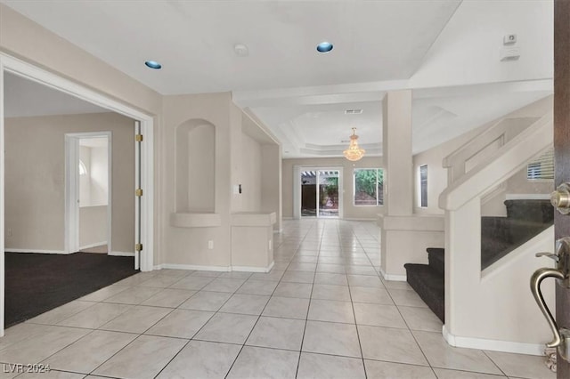 entryway with stairway, baseboards, light tile patterned flooring, and a raised ceiling