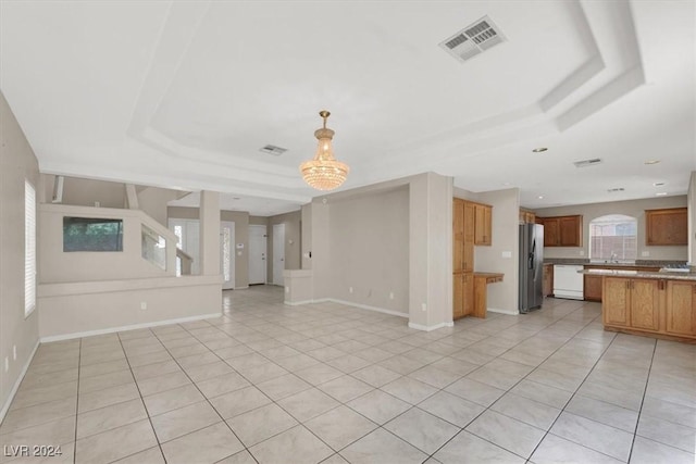 unfurnished living room featuring a raised ceiling, visible vents, baseboards, and light tile patterned floors