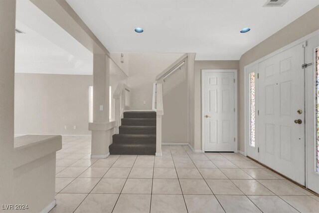 entrance foyer with light tile patterned flooring, baseboards, a healthy amount of sunlight, and stairs
