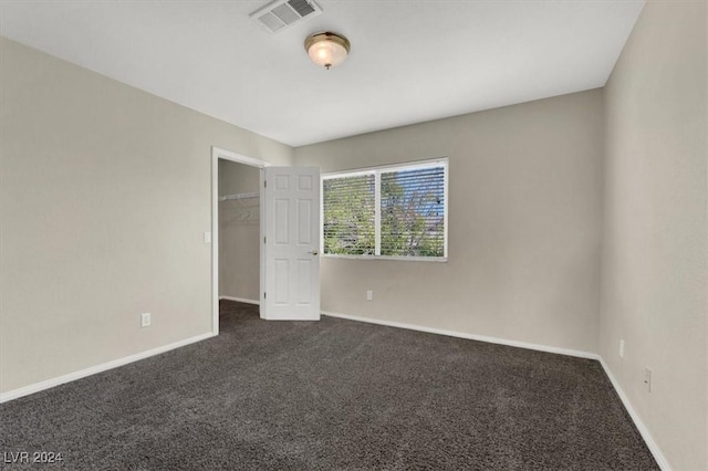 unfurnished room with dark carpet, baseboards, and visible vents