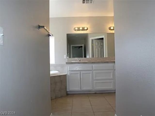 bathroom featuring vanity, tile patterned flooring, and a bath