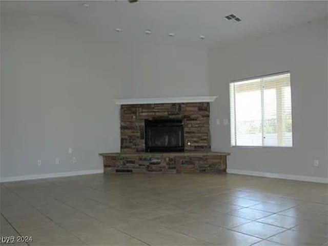 unfurnished living room featuring light tile patterned floors and a stone fireplace