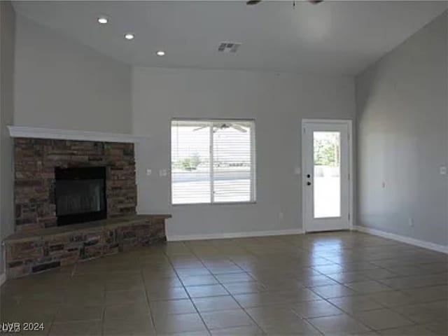 unfurnished living room with a stone fireplace and tile patterned flooring