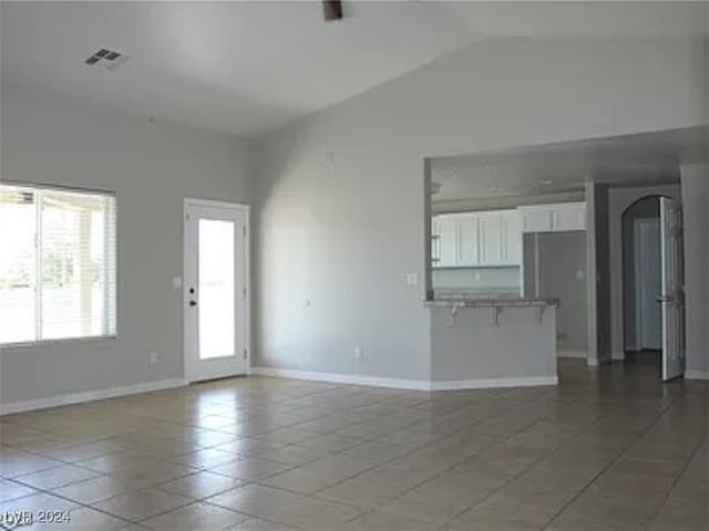 unfurnished living room featuring vaulted ceiling and tile patterned floors