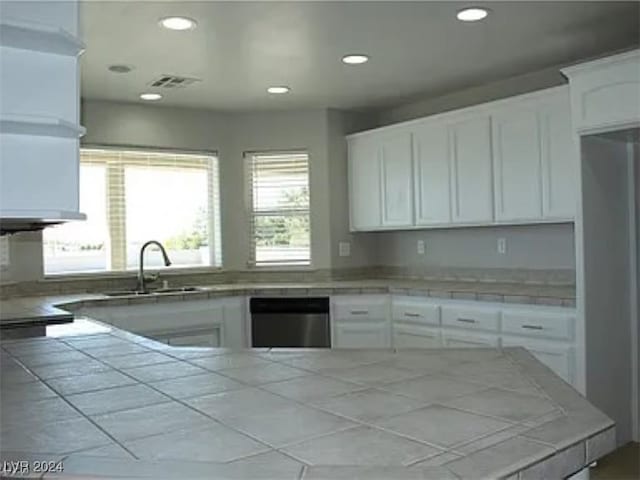 kitchen with white cabinetry, tile counters, dishwasher, and sink