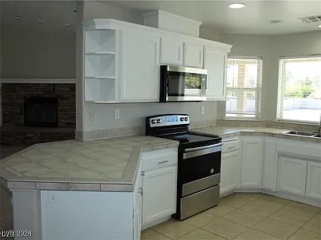 kitchen with stainless steel appliances, white cabinets, and tile counters