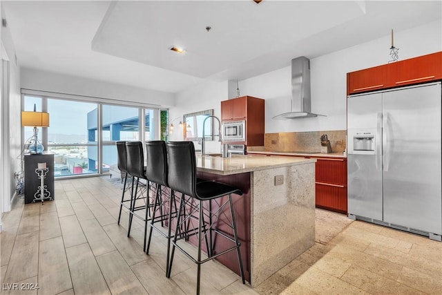 4471 Dean Martin Dr Unit 606, Las Vegas, NV 89103 - kitchen with appliances with stainless steel finishes, wall chimney exhaust hood, a center island with sink, decorative backsplash, and a kitchen breakfast bar