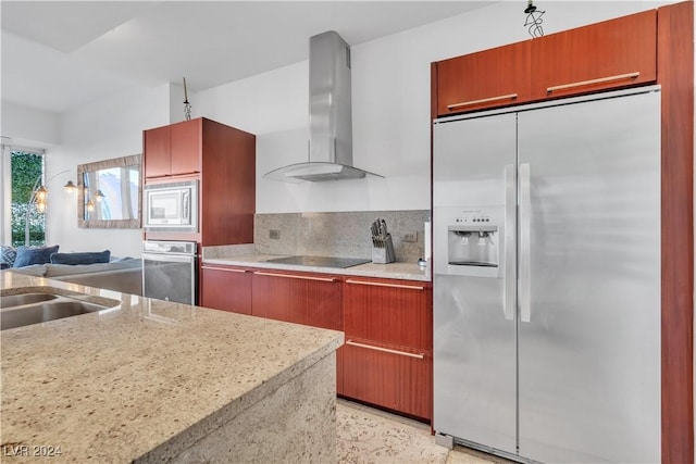 kitchen featuring sink, wall chimney exhaust hood, light stone counters, decorative backsplash, and appliances with stainless steel finishes