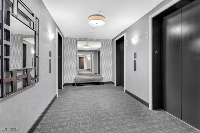 hallway featuring elevator and dark carpet