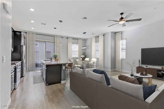 living room featuring light hardwood / wood-style floors, ceiling fan, and sink