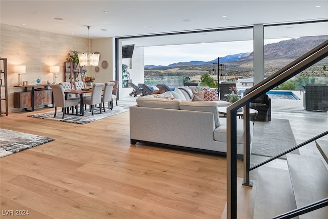 living room with a wall of windows, an inviting chandelier, and light hardwood / wood-style flooring