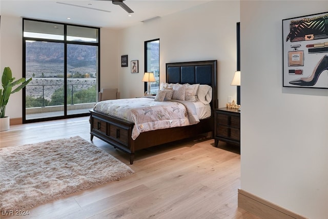 bedroom featuring light wood-type flooring, access to outside, ceiling fan, and expansive windows