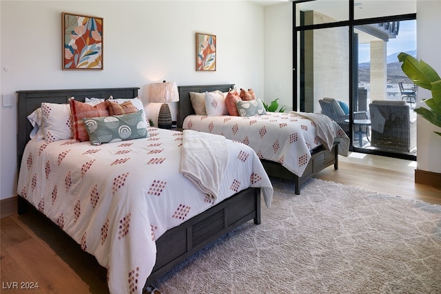 bedroom with wood-type flooring and expansive windows