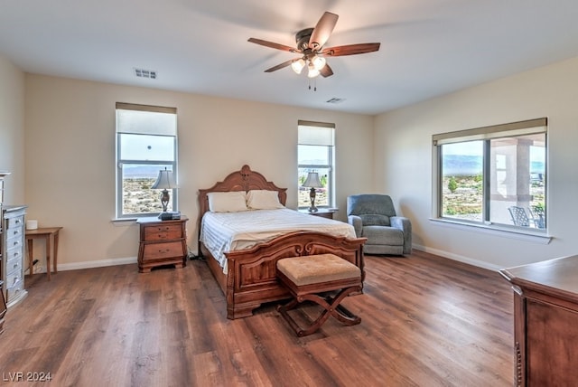 bedroom with multiple windows, dark hardwood / wood-style flooring, and ceiling fan