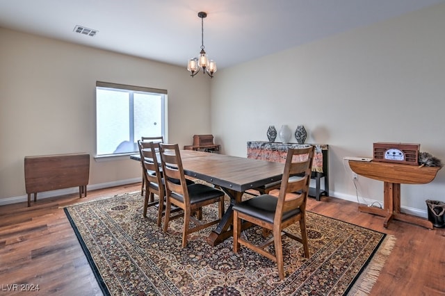 dining space featuring dark wood-type flooring and an inviting chandelier