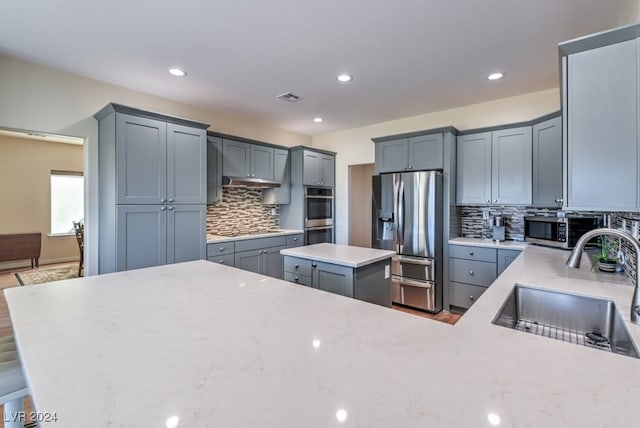 kitchen with decorative backsplash, appliances with stainless steel finishes, a center island, and sink