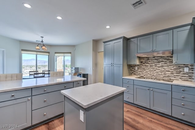 kitchen featuring gray cabinets, decorative backsplash, stovetop, and a kitchen island